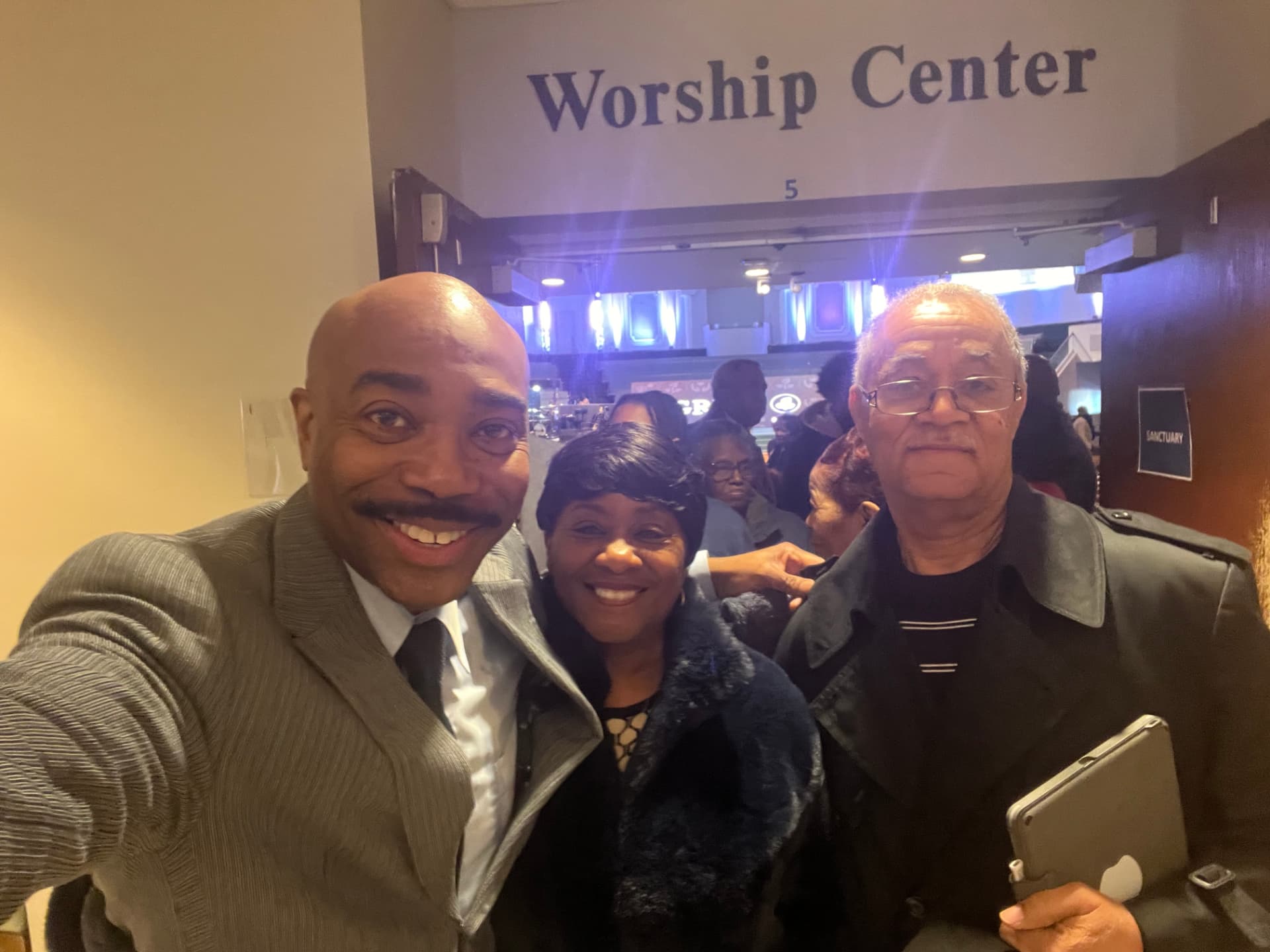 Dr. Orr taking a selfie with a smiling couple at the Worship Center entrance