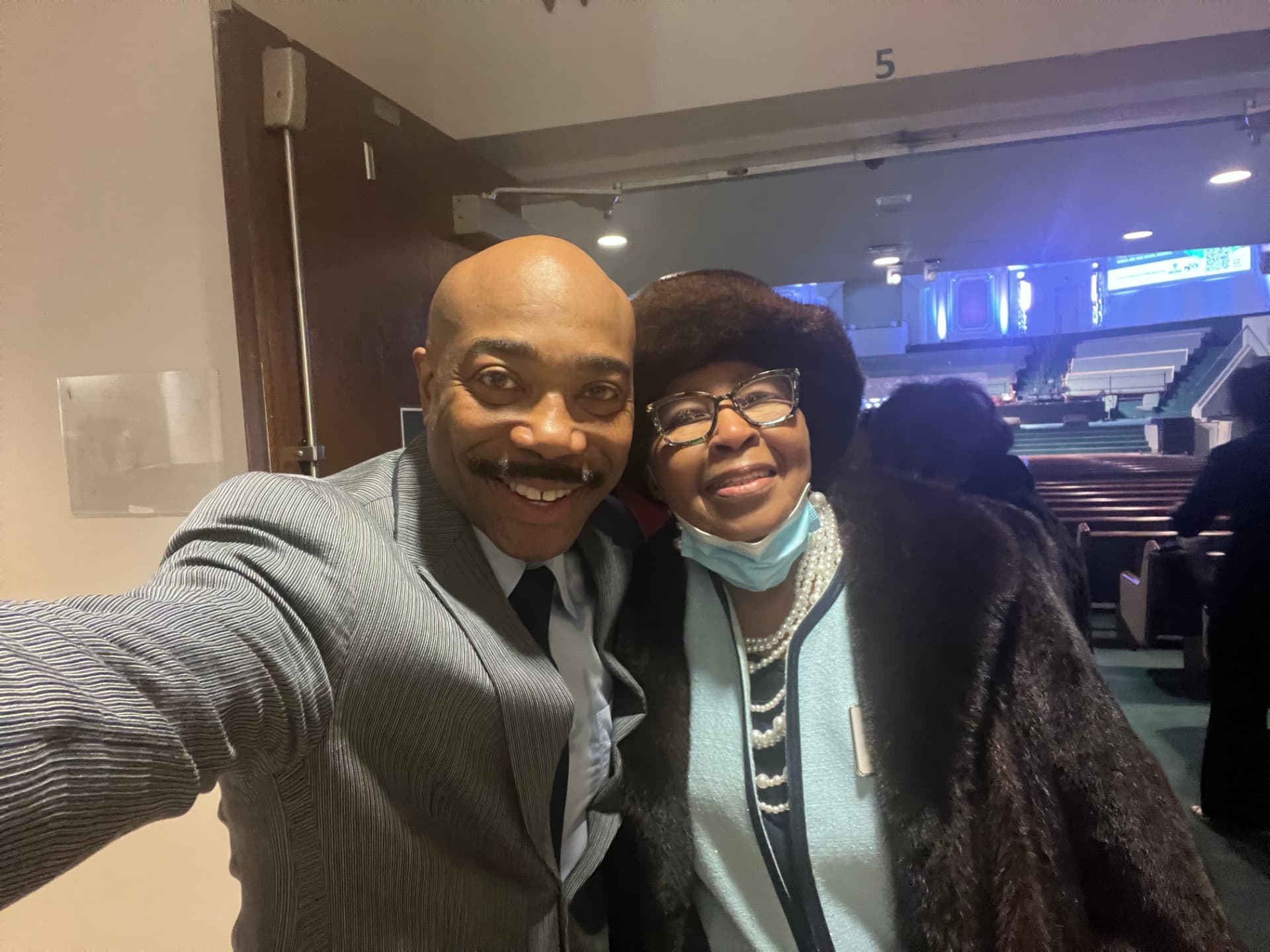 Dr. Orr taking a selfie with a church member in pearls and a fur coat at the Worship Center