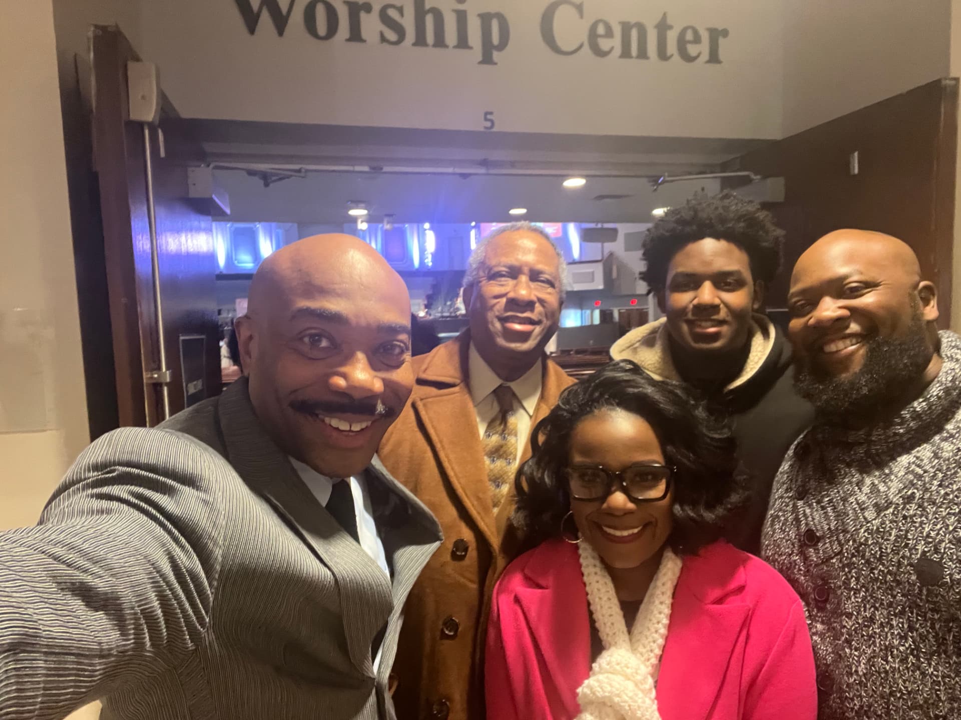 Dr. Orr taking a selfie with a group of four church members under the Worship Center sign